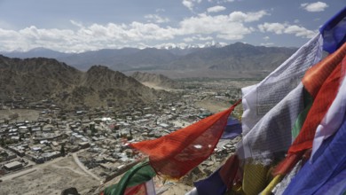 City view with prayer flags in the foreground and mountain scenery in the background under blue