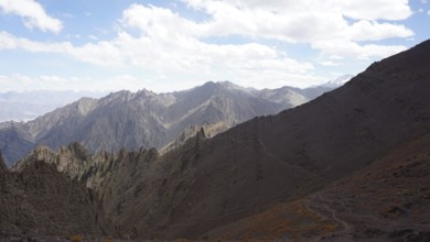 Rocky mountain range under cloudy sky and wide valley, trekking at Stok La Pass in Ladakh,