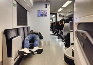 Sleeping man lying out early in the morning on the Wupper-Express RE 4 from National Express,