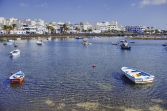 Coastal town with lagoon (Charco de San Ginés), scattered boats on calm water, white buildings on