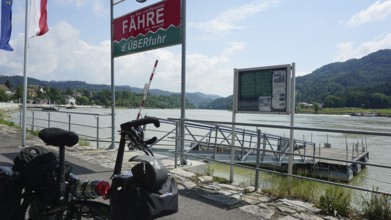 Cycling in front of a ferry with a view of the Danube and mountains, cycling on the Danube cycle