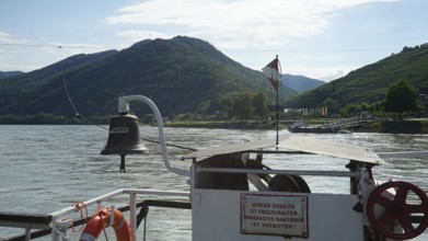 Ferry view of the Danube with flag and green mountains, long-distance cycle path, Danube cycle