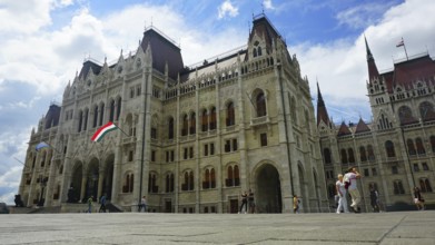 Parliament in Budapest, Impressive historic building in daylight with waving flag and people