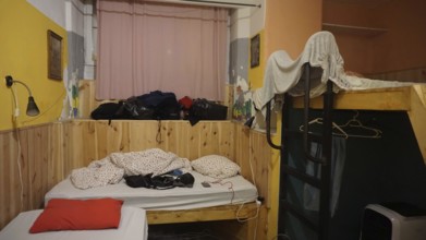 Simple hostel room with bunk bed and messy packed luggage, Budapest