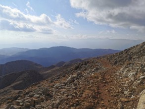 Rocky mountain trail with views of surrounding mountains and clouds, climbing Tahtali Dagi, Lycia,