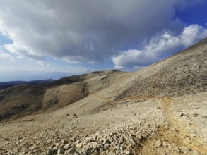 Open mountain trail on Tahtali Dagi under a partly cloudy sky with a wide view, climbing Tahtali