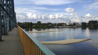 River landscape with two sandbanks in the Vistula with metal bridge, clouds and view of Torun city,