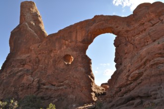 Turret Arch, an impressive sandstone rock arch under a clear blue sky, formed by natural erosion,