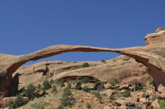 Landscape Arch, an impressive natural stone bridge against bright blue sky, Arches National Park,