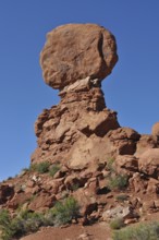 A massive, balanced rock formation in the midst of a barren desert landscape, Arches National Park,