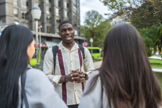 Young diverse friends standing outdoors in an urban setting, conversing casually on a sunny day,