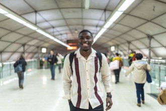 Young african man smiling, wearing a backpack and casual clothes, walking confidently through a