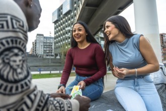 Diverse group of young adult friends enjoying a casual game of cards and laughing together in an