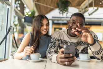 Multiracial couple enjoying a cheerful date, sharing happy moments while viewing media on a mobile