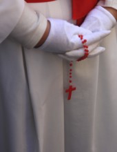 White dress with red sherp, white gloves and a red rosary