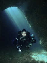 In an underwater cave, a diver moves through bright blue light. Fraskeric dive site, Stoja, Pula,