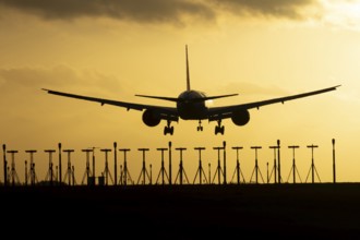 Boeing 777 commercial passenger jet aircraft in flight on approach to land over runway lights