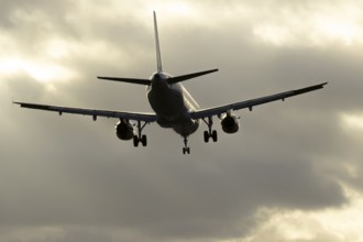 Commercial passenger airliner jet aircraft in flight on approach to land at sunset at London