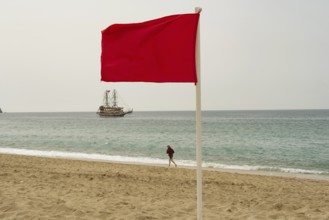 Alanya, Turkey. April 6th 2021 Red flag flying on an empty Turkish beach in the tourist resort city