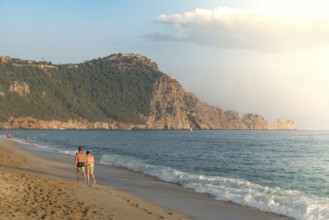 A couple walk along an empty Cleopatra Beach at sunset in the Turkish holiday resort town of Alanya