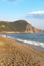 A couple walk along an empty Cleopatra Beach at sunset in the Turkish holiday resort town of Alanya
