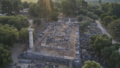 Temple of Zeus in backlight, architectural remains in a forest landscape with a visible stone