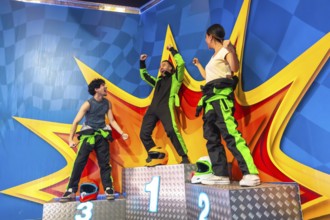 Joyful friends celebrating success on a racing podium, with the winner raising arms in triumph,