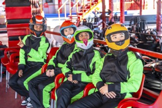 Group of young diverse adults wearing race suits and helmets, sitting on chairs and anticipating a