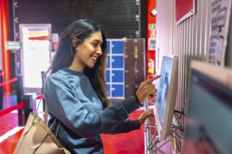Young woman smiling while interacting with a touchscreen display, checking in for a karting