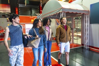 Group of diverse young adult friends smiling, walking, and looking around at an indoor karting