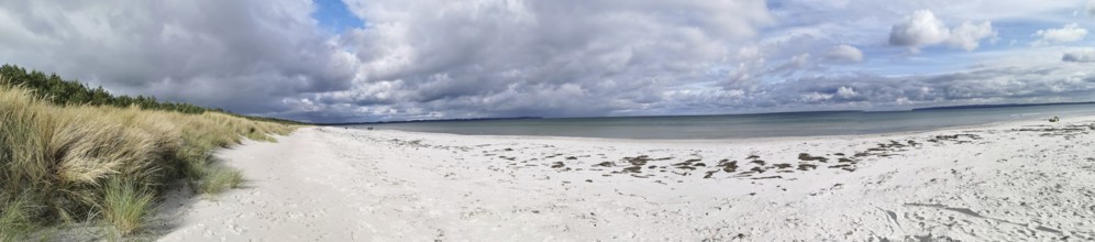 Lonely coastal landscape with white sandy beach, cloudy sky and grassy dunes, Rügen, Baltic Sea