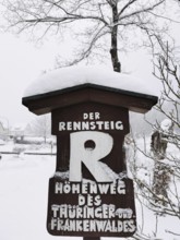 Snowy sign of the Rennsteig in wintry rural surroundings, hiking in the Franconian Forest nature