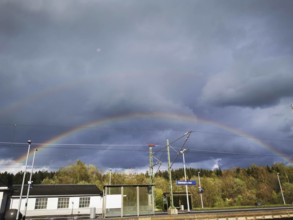 Double rainbow over a small train station area under a cloudy sky, Steinbach am Wald, Rennsteig,