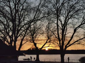 People walk along the Müggelsee waterfront at sunset, Berlin