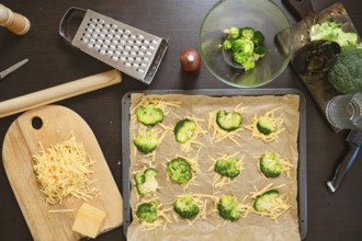 Overhead view of ingredients for smashed broccoli with cheese are on dark kitchen table