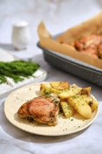 Roasted chicken and potato wedges. Baking tray is seen in the background with more chicken. The