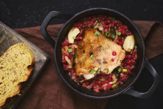 A chicken piece is cooking in a pot filled with lingonberry and garlic. A slice of bread is placed