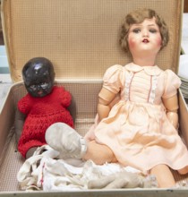 Dolls from 1920s to 1940sin a suitcase, one with articulated limbs and painted features, the other