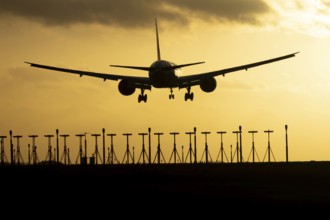 Boeing 777 commercial passenger jet aircraft in flight on approach to land over runway lights