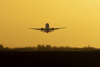 Airbus commercial passenger airliner jet aircraft taking off in flight silhouette at sunset at