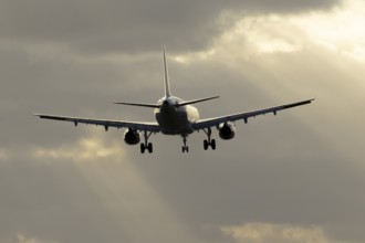 Commercial passenger airliner jet aircraft in flight on approach to land at sunset at London