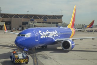 Phoenix, Arizona - A worker driving a tractor pushes a Southwest Airlines jet back from the gate as