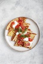Delicious pancakes with salmon and sour cream, breakfast, on a plate, rustic style, with cutlery