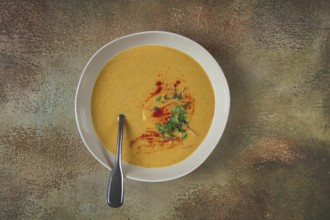 Pumpkin cream soup, in a white bowl on a textured background, top view, homemade, no people, rustic