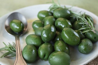 Chalkidiki olives, classic Greek green olive, on a plate, with a spoon, top view, no people