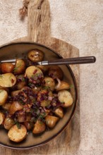 Succulent golden-brown roasted potatoes are served with sweet caramelized onions, garnished with