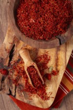 Spice saffron threads, in a wooden bowl, on a wooden table, top view, close-up