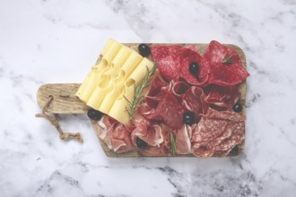 Assorted meat, appetizer, prosciutto, salami and ham, with maasdam cheese and olives, on a wooden