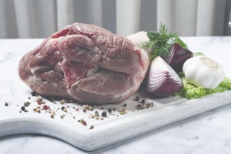 Raw pork knuckle, on a wooden chopping board, with spices, close-up, top view, no people