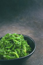Chuka salad, made from fresh seaweed, with sesame dressing, served in a black bowl